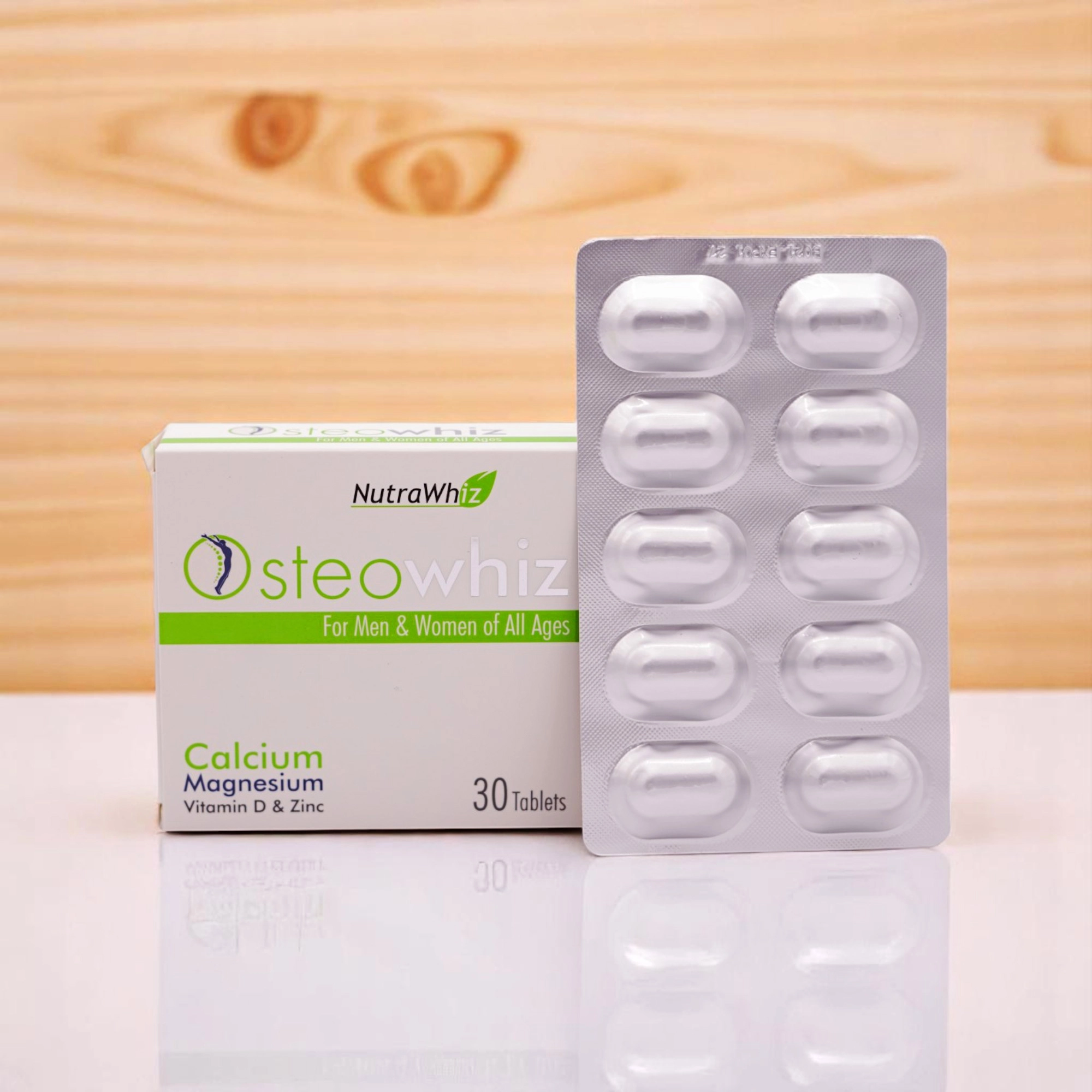 NutraWhiz Osteowhiz Calcium Magnesium Vitamin D & Zinc tablets, 30 tablets, in a white and green box and a blister pack of 10 white, oval-shaped tablets, set against a light wood background.